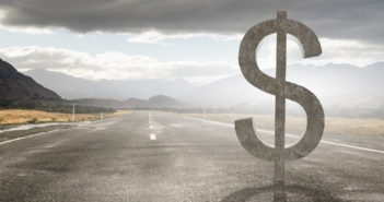 Big stone dollar currency sign on asphalt road