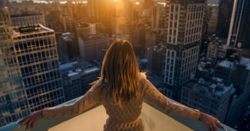 Rich woman enjoy the sunset standing on the balcony at luxury apartments in New York City. Luxury life concept. Succesful B businesswoman relax.