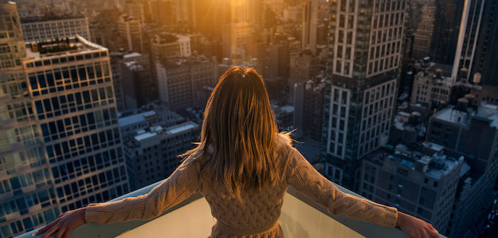 Rich woman enjoy the sunset standing on the balcony at luxury apartments in New York City. Luxury life concept. Succesful B businesswoman relax.
