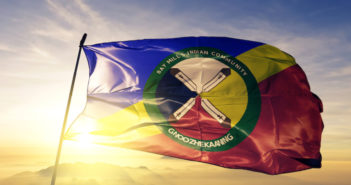 Bay Mills Indian Community flag textile cloth fabric waving on the top sunrise mist fog