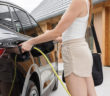 Young woman plugging a charger in electric car at modern house home